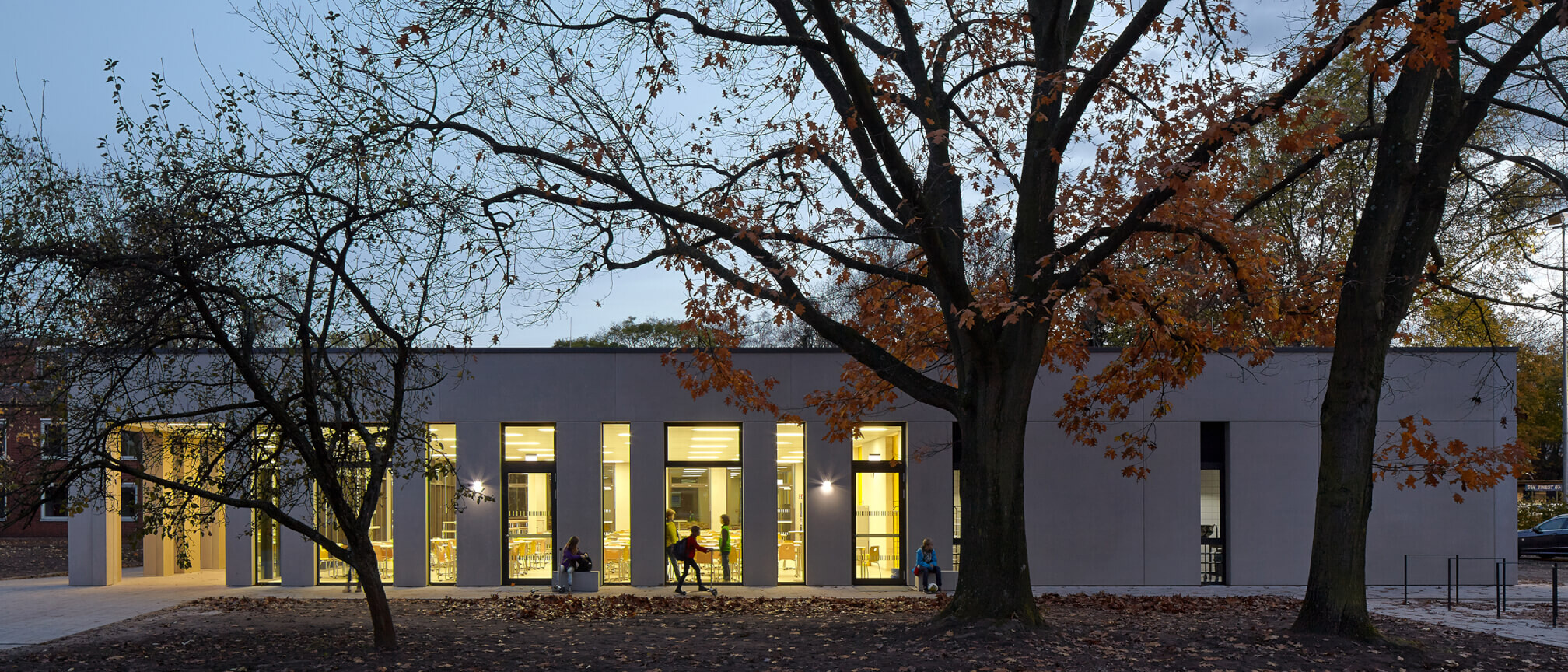 Seitenansicht der Schulmensa in der Abenddämmerung der Katharina-Henoth-Gesamtschule von Damrau Kusserow